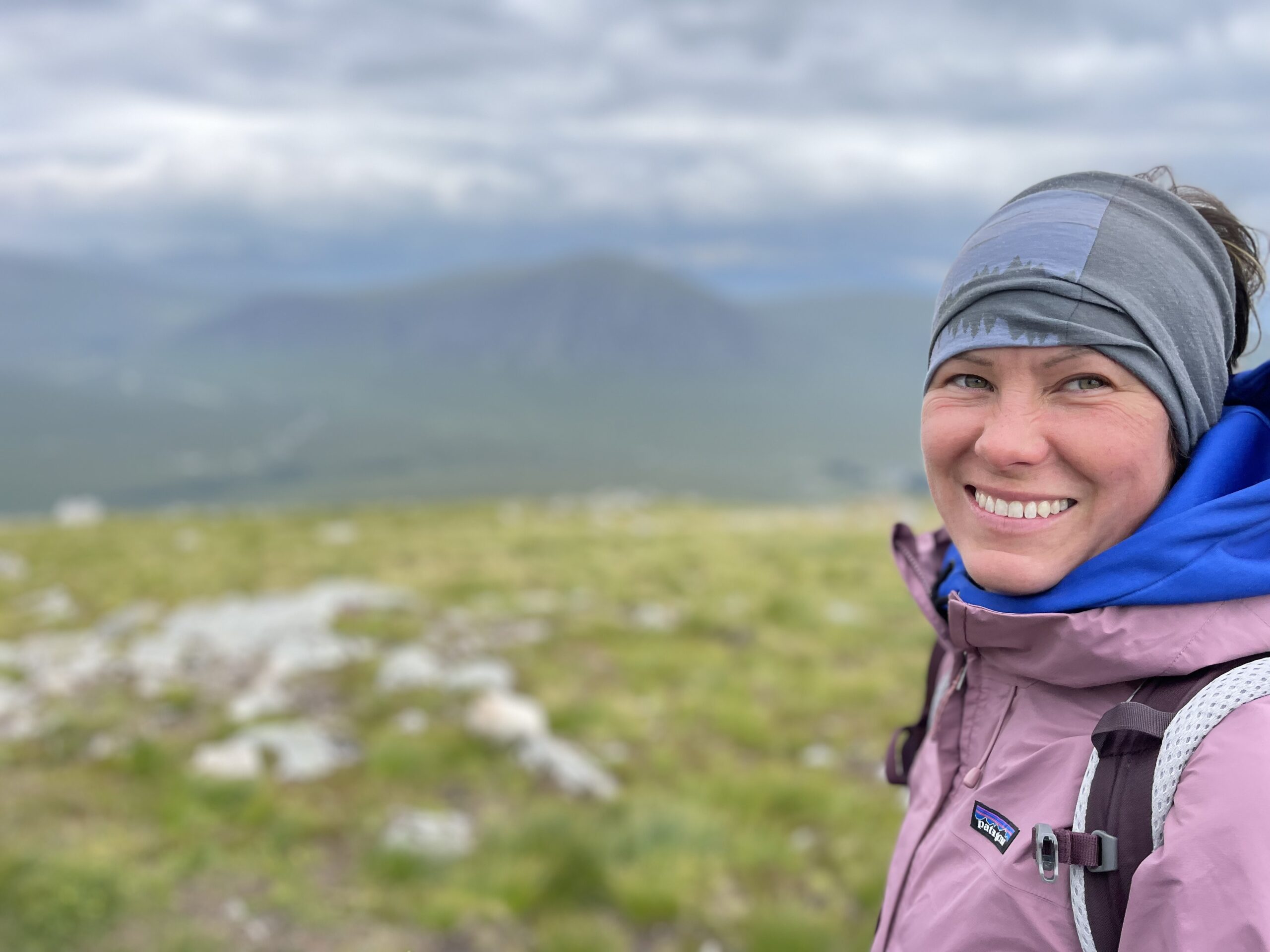 Frau mit kurzem dunkelbraunen Pferdeschwanz, schwarzem Sporttop und schwarzer langer Laufhose läuft eine lange, breite Treppe hoch